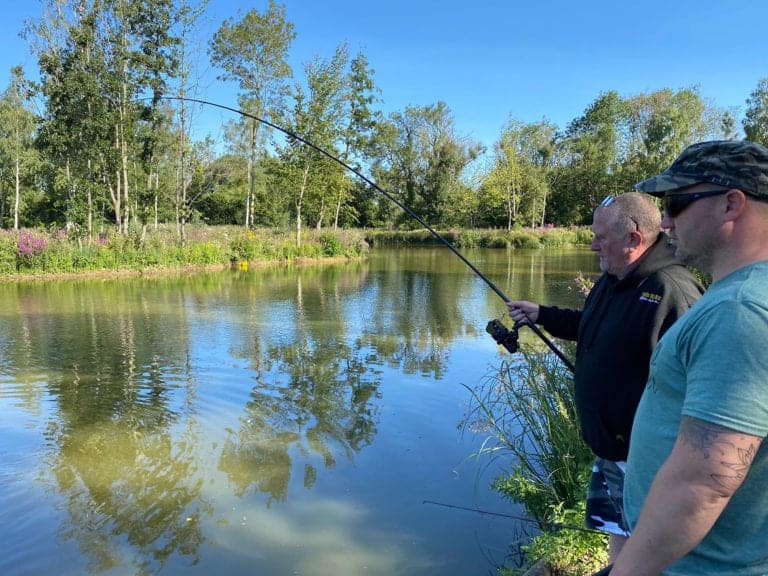 Two men fishing by a calm lake.