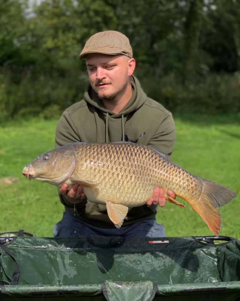 Man holding large carp fish outdoors