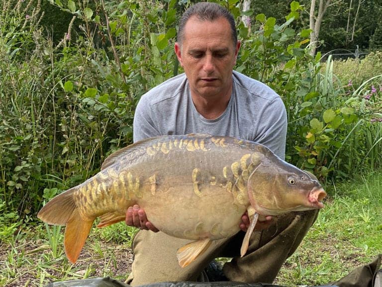 Man holding large fish in nature setting.