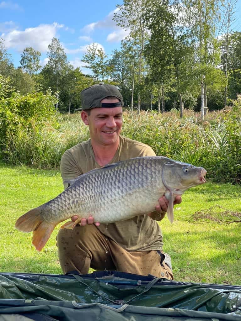 Smiling man holding a large fish in park.