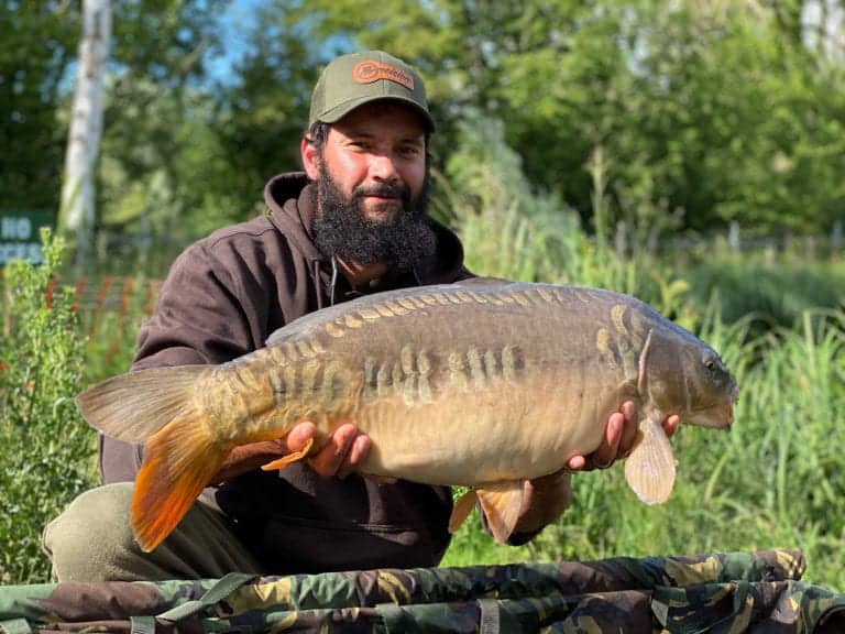 Man holding large fish in outdoor setting.