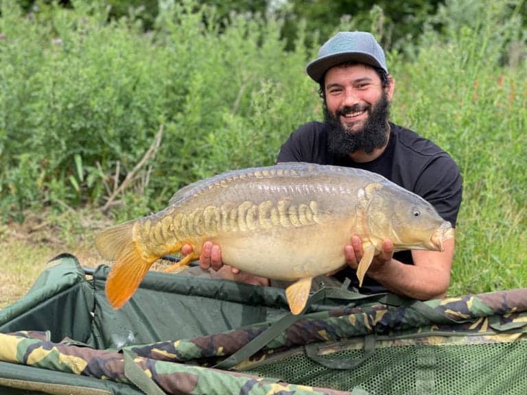 Man holding a large carp fish outdoors.