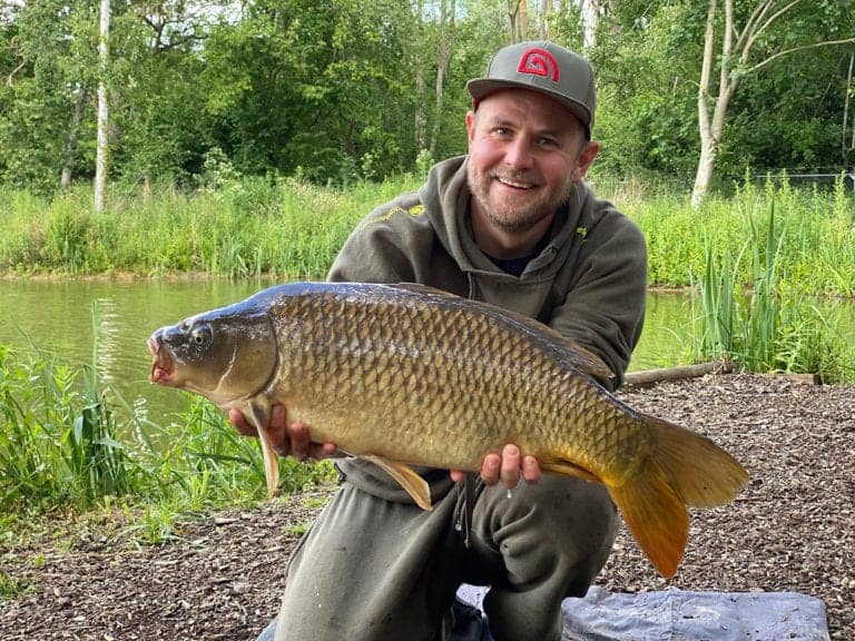 Man holding large fish by a lake