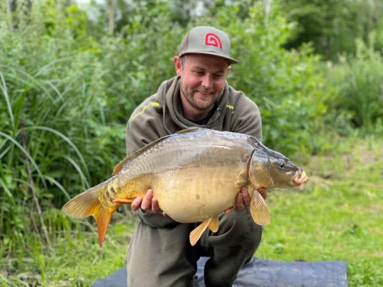 Smiling angler holding a large carp in nature.
