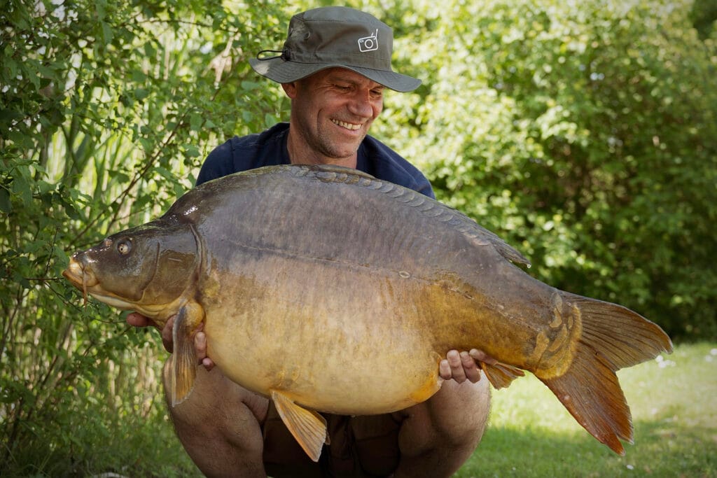 Man holding large carp fish outdoors
