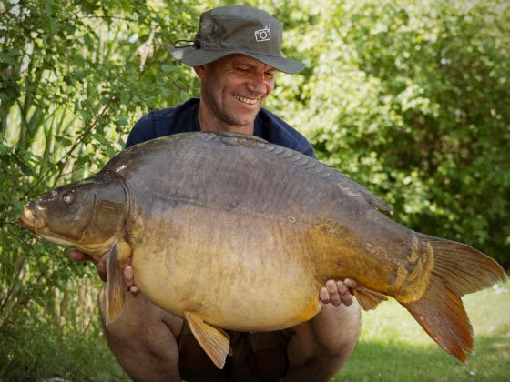 Man holding large carp fish outdoors