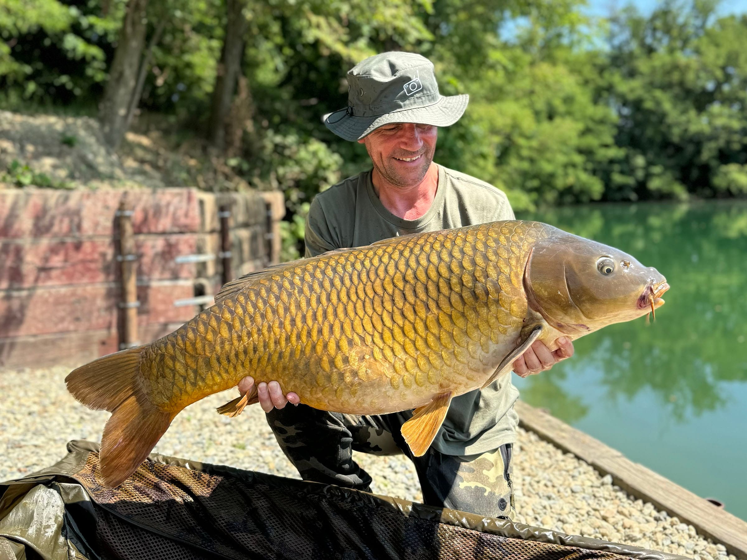 Man holding large carp by lake
