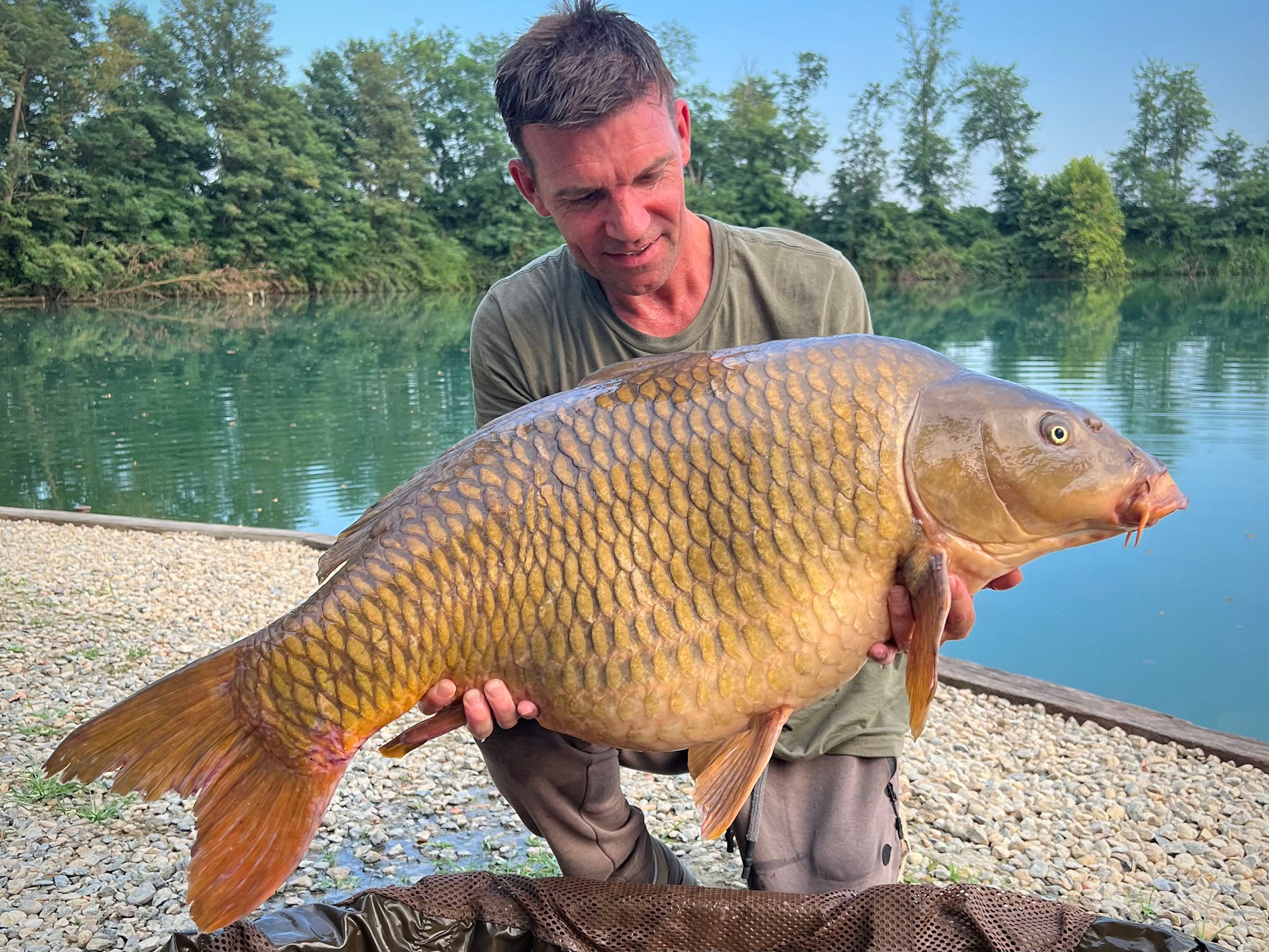 Man holding large carp by the lake