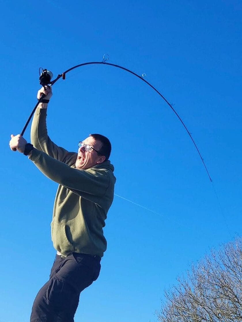 Man casting fishing rod under clear blue sky.