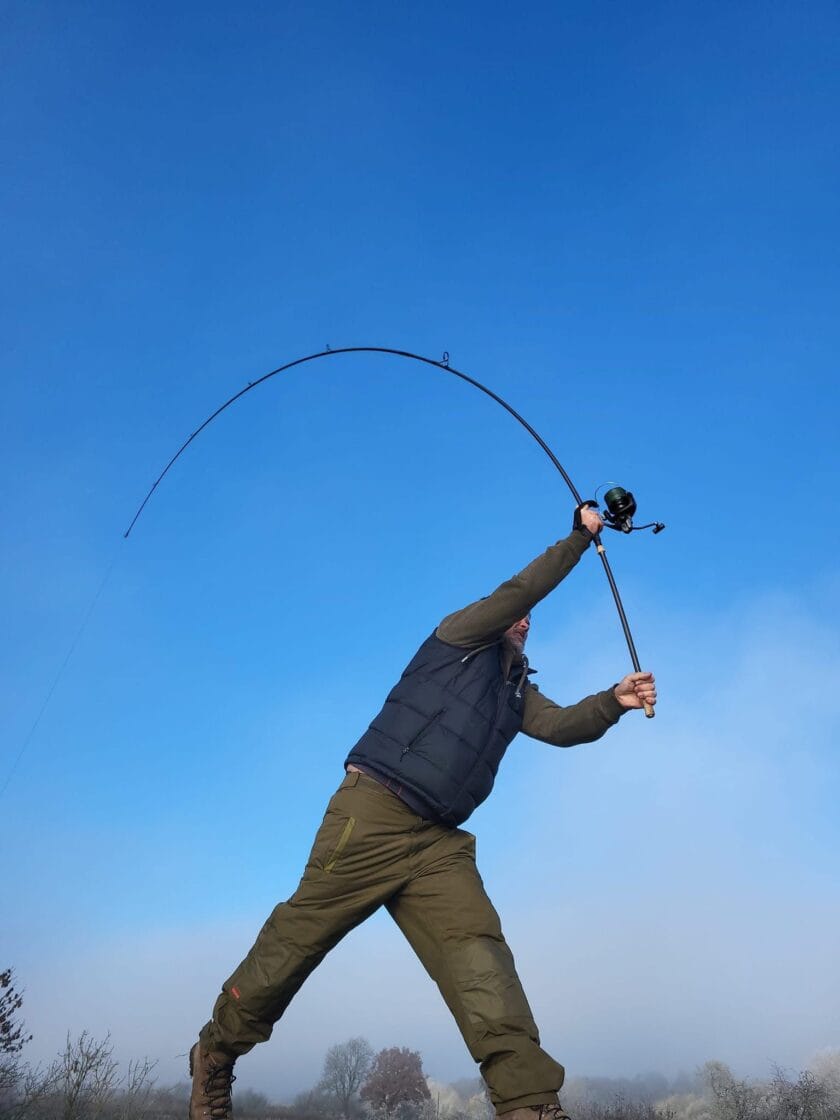 Person casting fishing rod under clear blue sky.