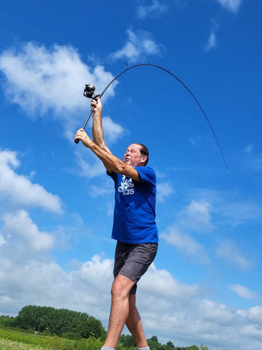 Man casting fishing rod under blue sky.