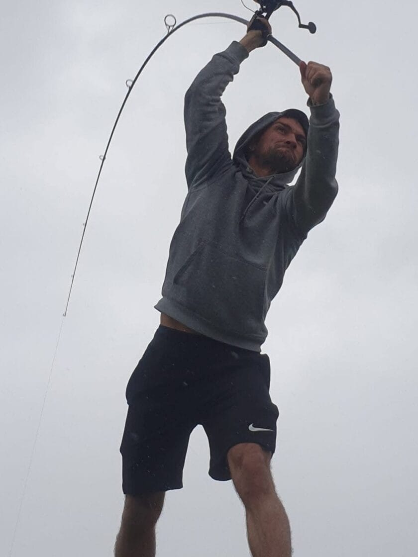 Man casting fishing rod on cloudy day.