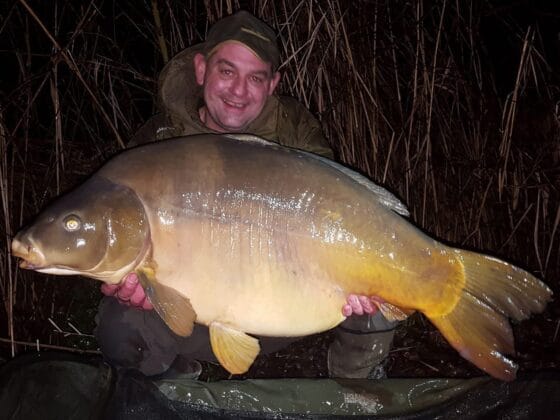 Angler holding large carp at night